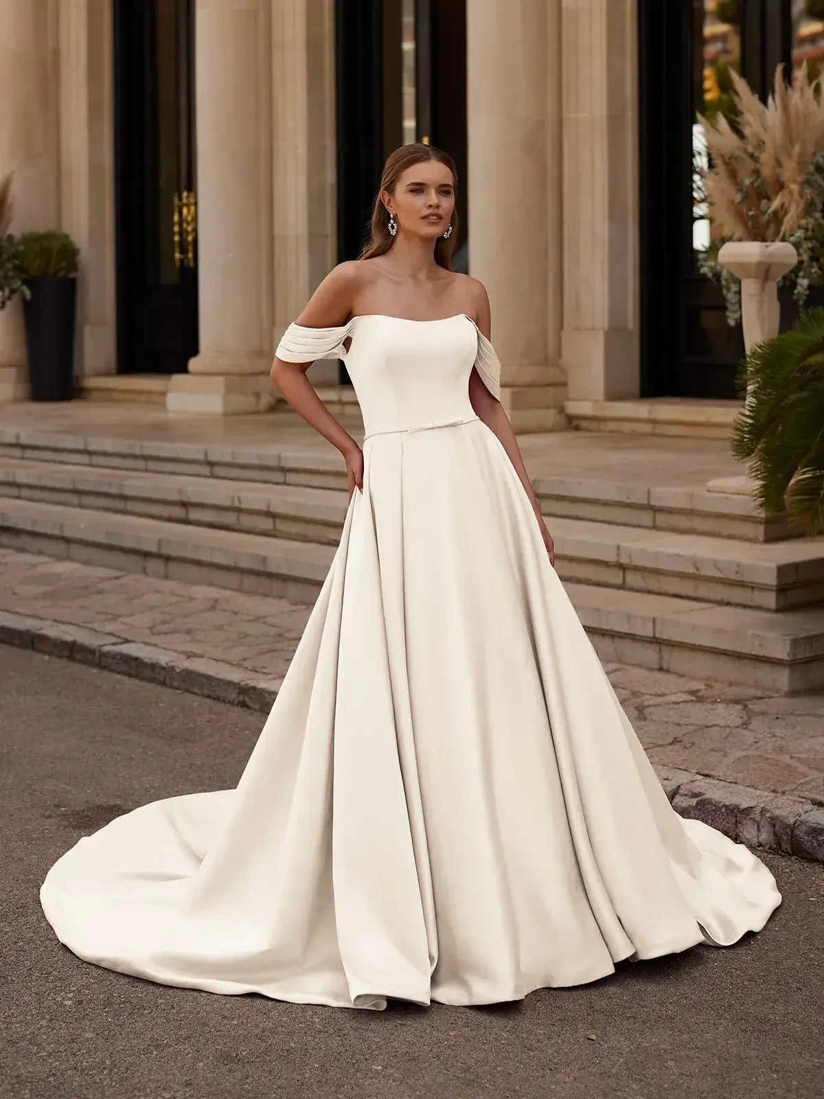 model is wearing an off the shoulder a-line wedding gown